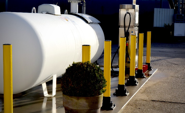 Yellow SlowStop rebounding bollards protect white gas tank and gas pump from accidental vehicle damage. Yellow SlowStop rebounding bollards protect white gas tank and gas pump from accidental vehicle damage.